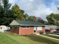Small brick home with a dark green shingle roof